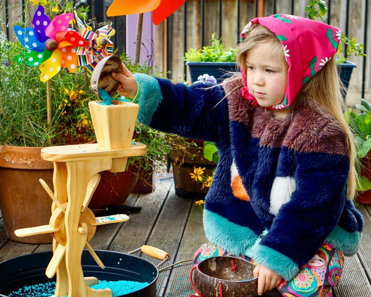 Child playing with a wooden toy outdoors on a wooden deck.